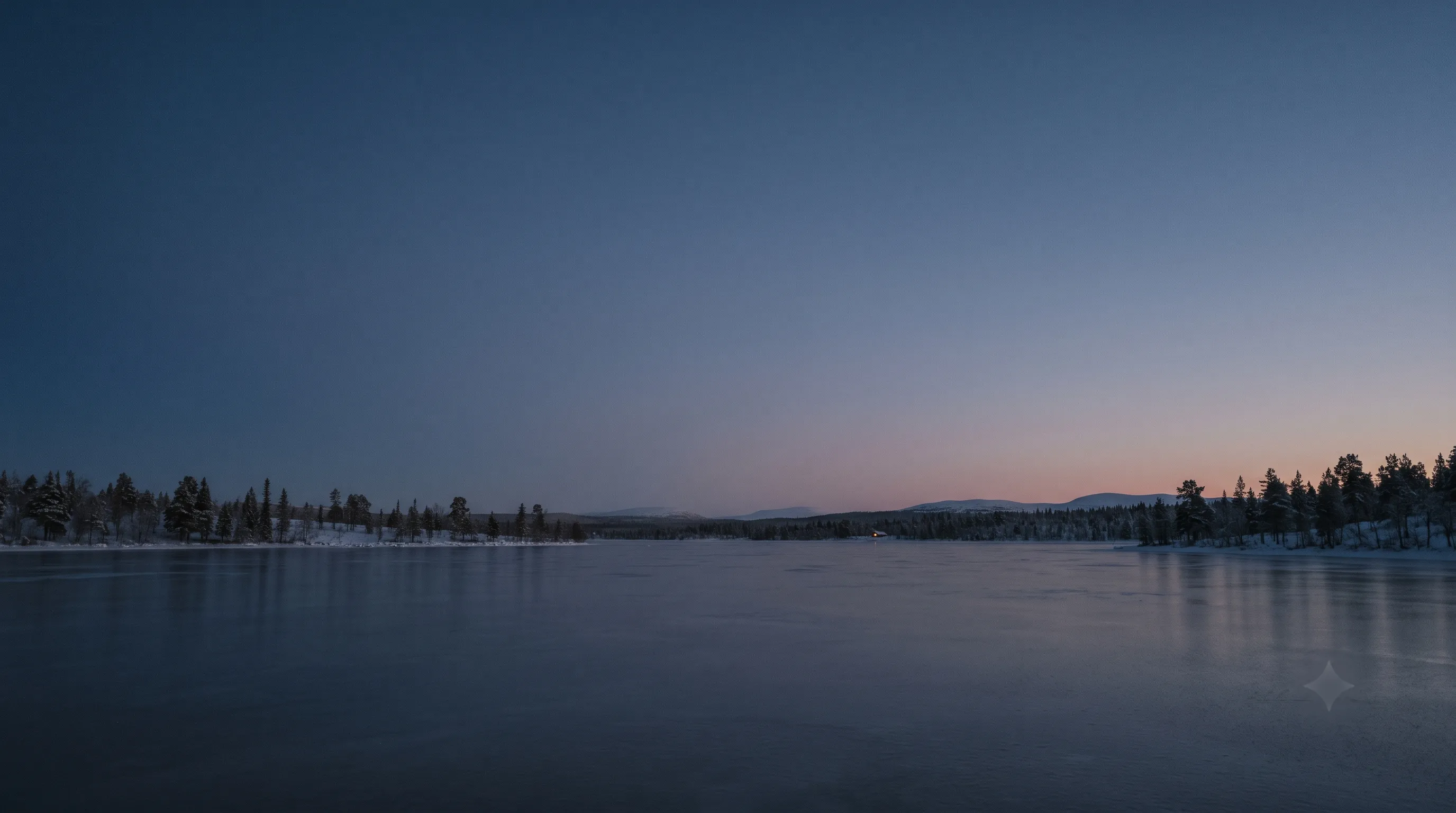 A vast frozen lake beneath a low tree line at blue hour in Finnish Lapland.